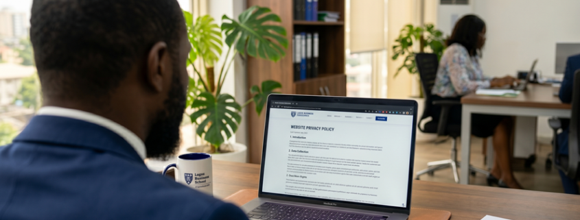 Nigerian business professional signing a compliance document beside a laptop showing a privacy policy page in a bright office