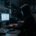 Hooded figure in dark room illuminated by monitor showing blurred Nigerian database rows, blue light, cinematic atmosphere