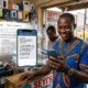 Featured image alt text Nigerian business owner reading an AI assistant answer on a phone instead of a search results page